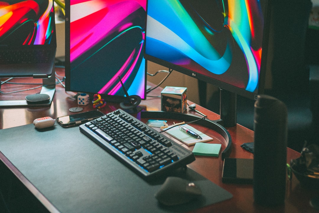 Two computer monitors with colorful screens on a wooden desk